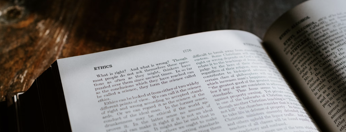 Open book on a wooden table with a chapter titled “Ethics” visible.