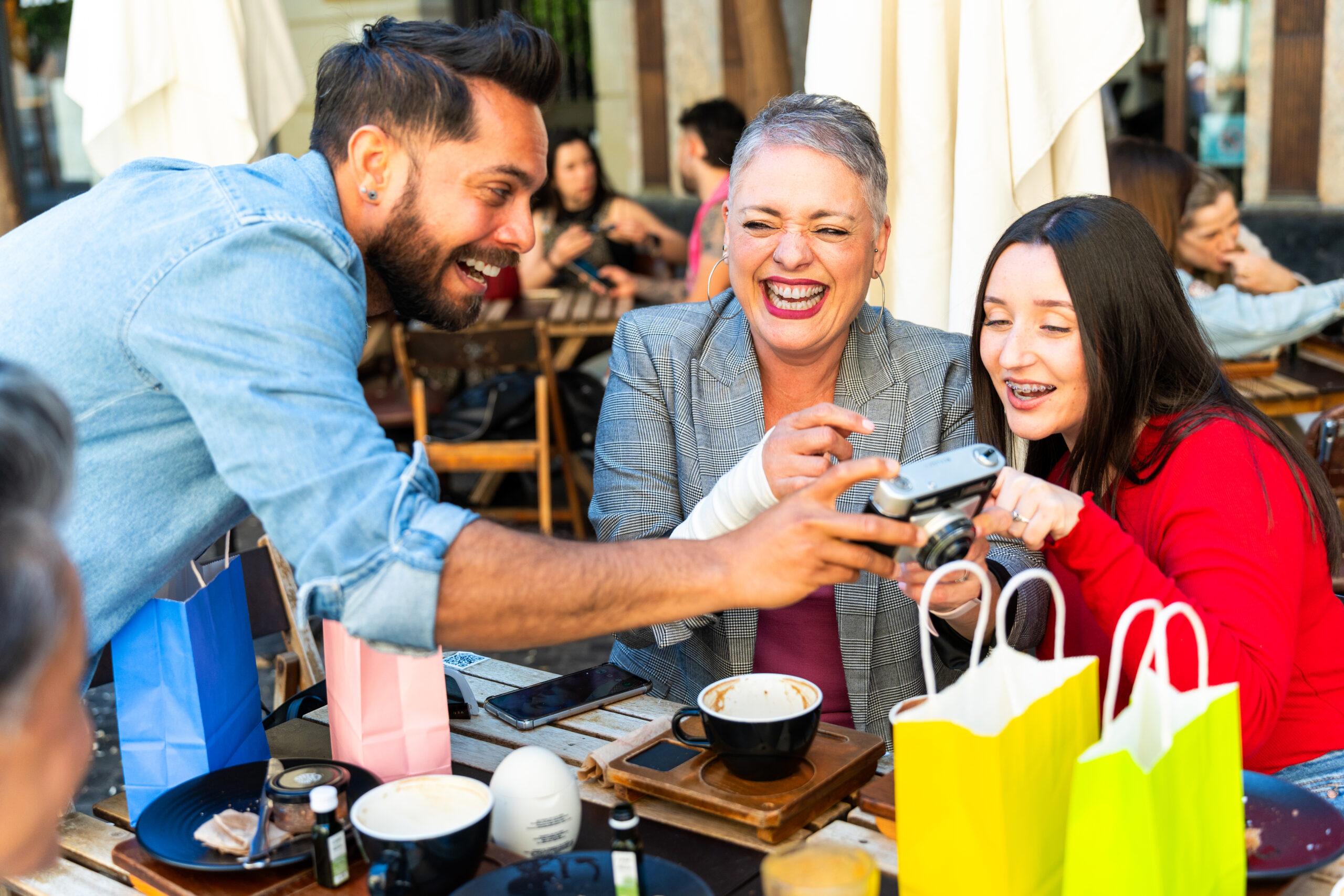 Customer Loyalty Strategies That Strengthen Your Brands Retention - Friends Laughing At Table Whilst Looking at Photos