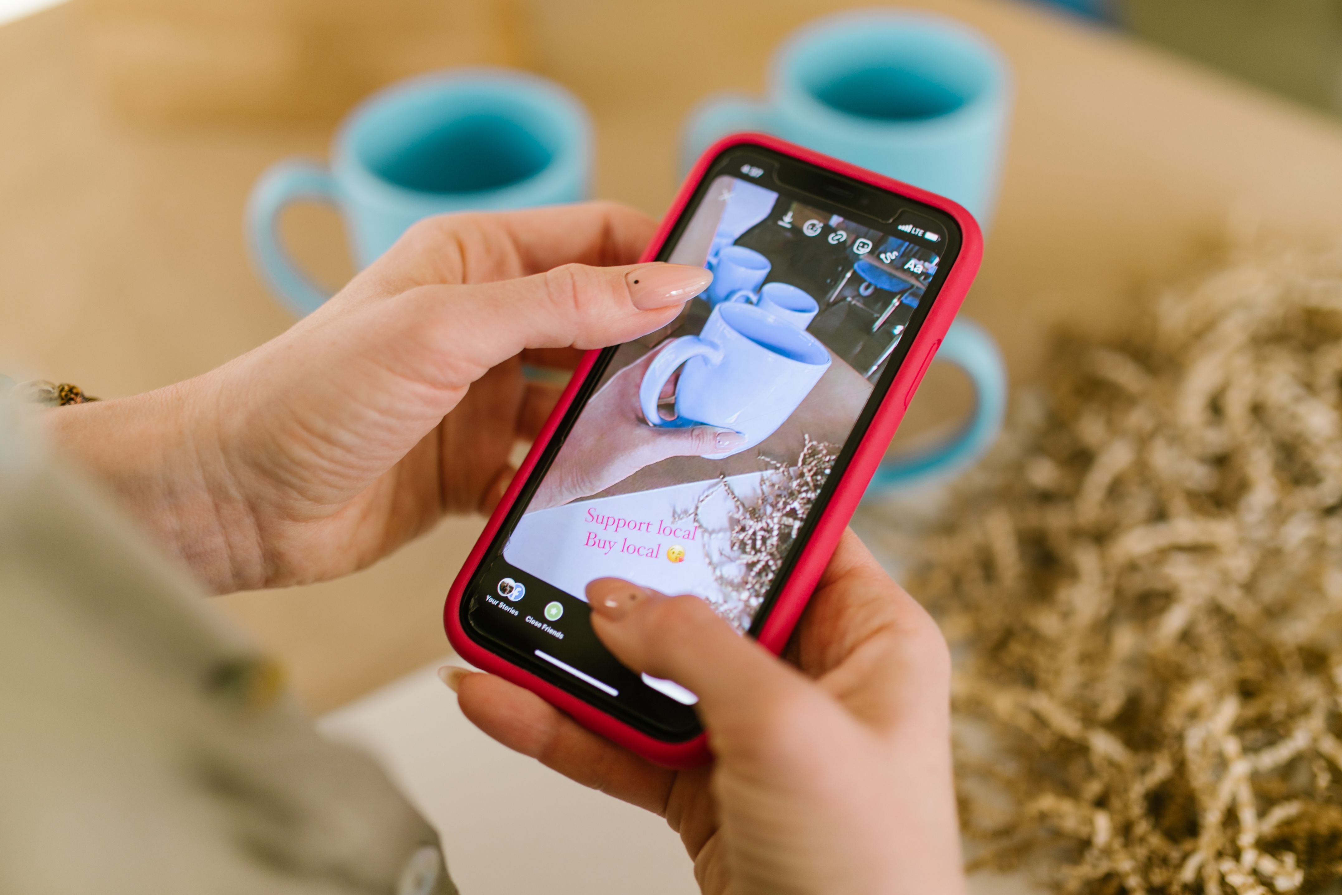 Close-up of hands using a smartphone to support local businesses online.