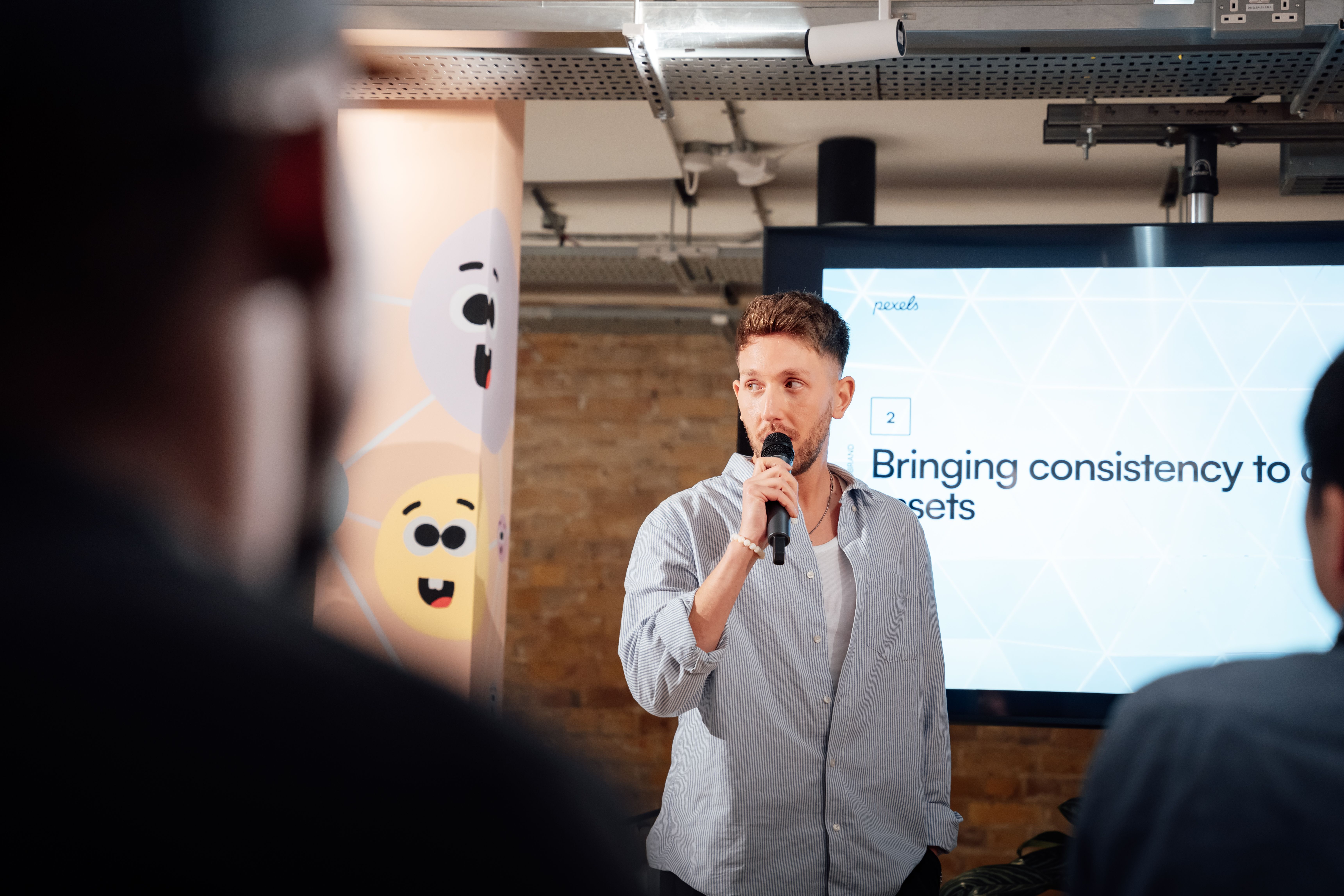 Man presenting with microphone at a business event in London, engaging audience.