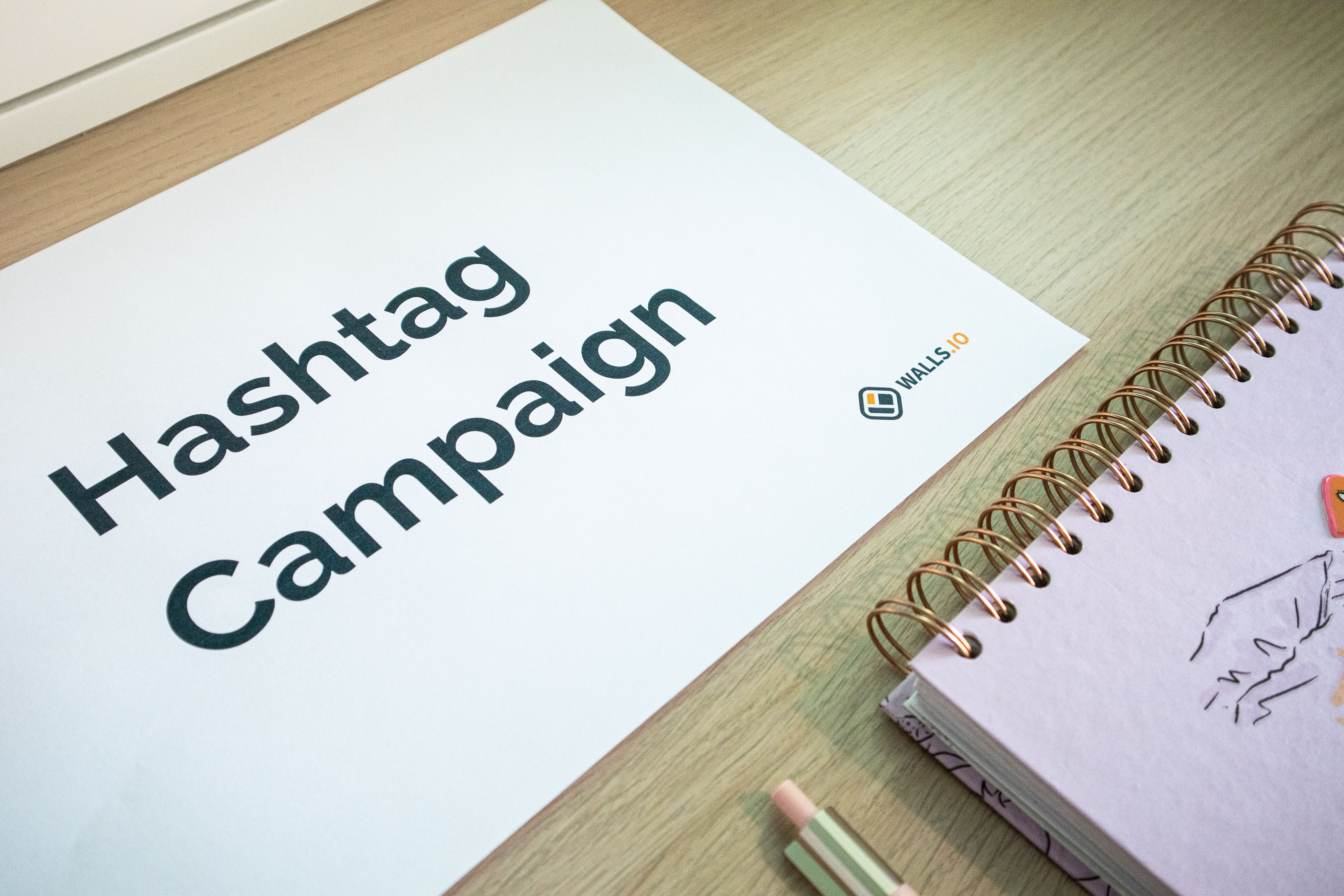 A clean office desk setup featuring hashtag campaign marketing materials and a planner.
