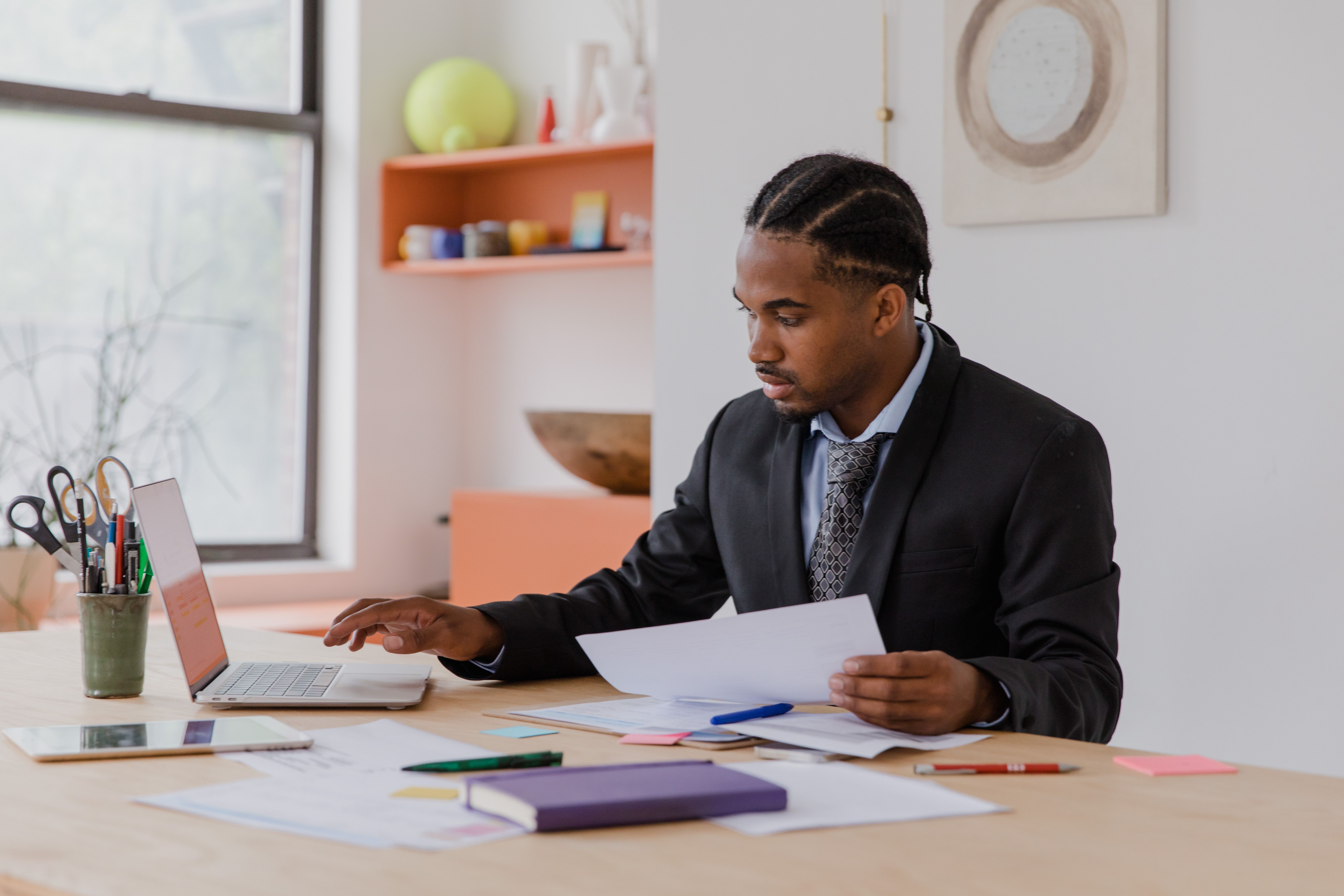 Focused businessman working with laptop and documents in a modern office setting.