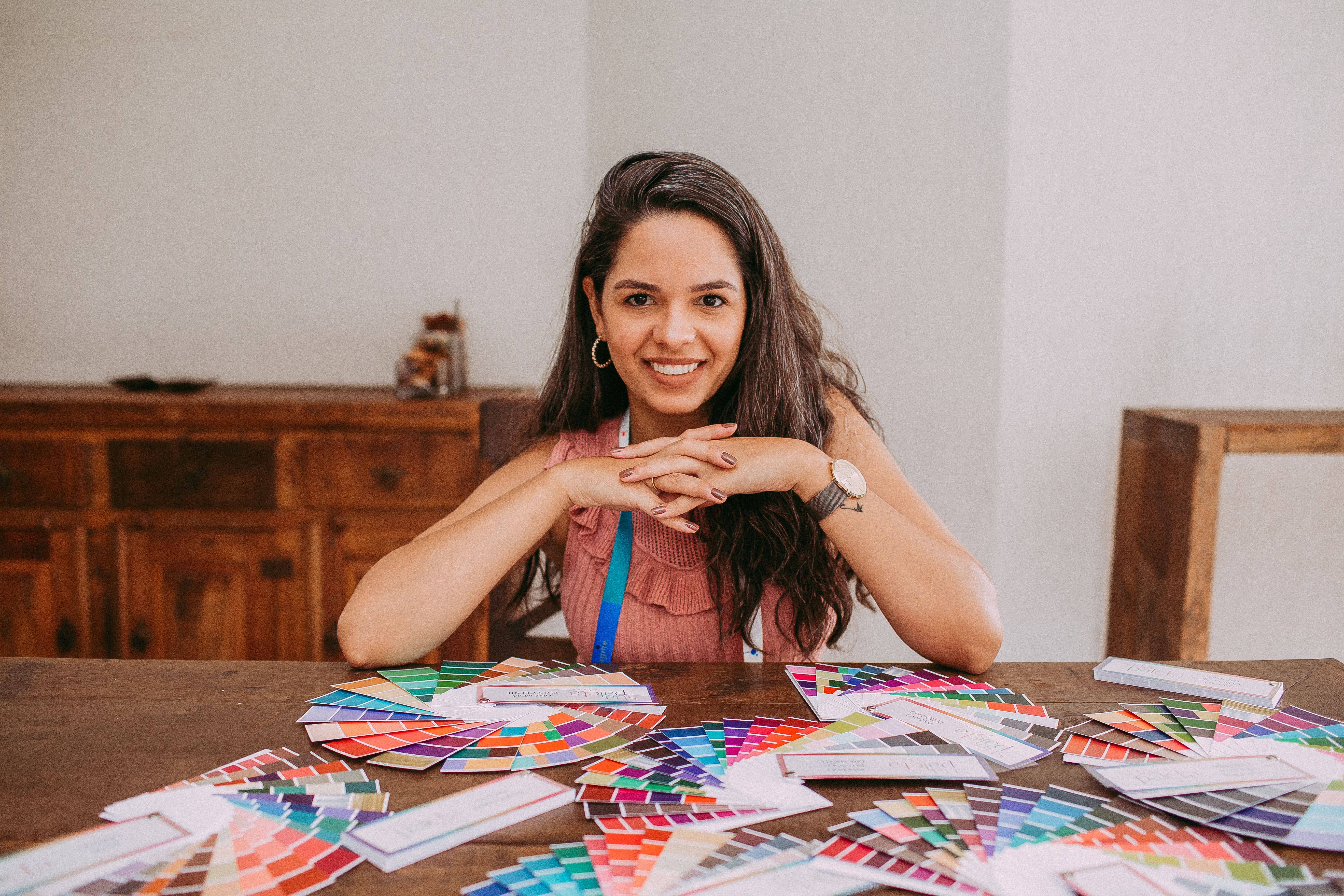 Smiling designer with color palettes on desk showcasing creativity indoors.